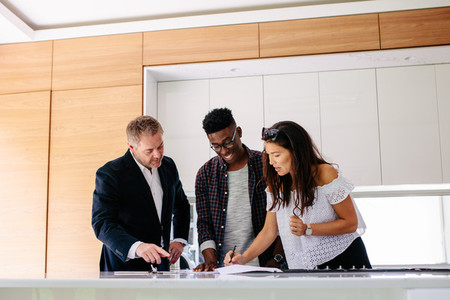 Interracial couple with realtor signing mortgage contract