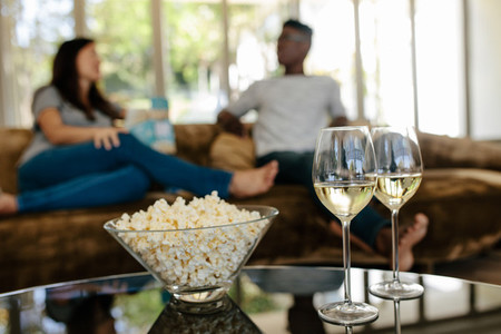 Popcorn and drinks with couple relaxing in background