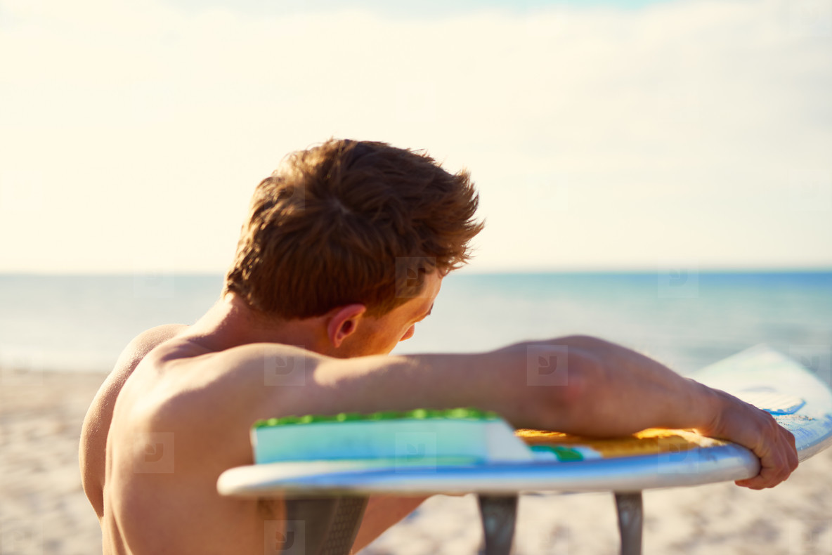 Male Surfer Checking the Surface of his Surfboard