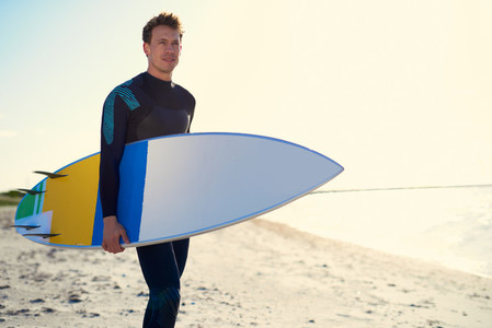 Handsome sporty surfer posing with his surfboard