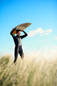 Muscular surfer balancing his board on his head