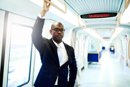Businessman in a Subway Train Holding on Railing