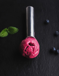 Blueberry ice cream scoop over black slate stone background