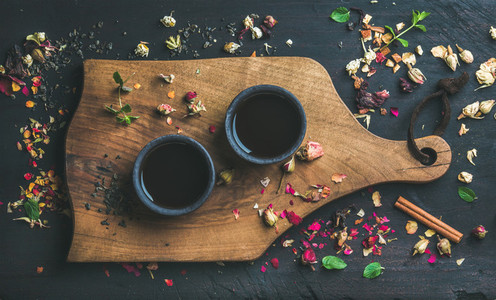 Chinese black tea in black stoneware cups on wooden board