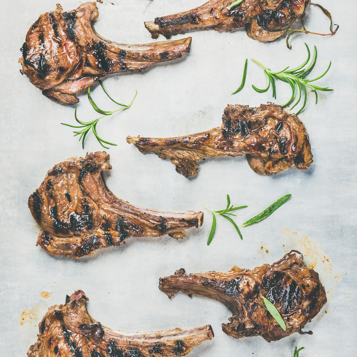 Grilled lamb ribs with fresh rosemary over metal tray background