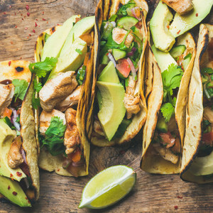 Tacos with chicken avocado fresh salsa and limes square crop