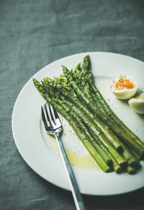 Cooked asparagus with soft boiled egg and herbs copy space