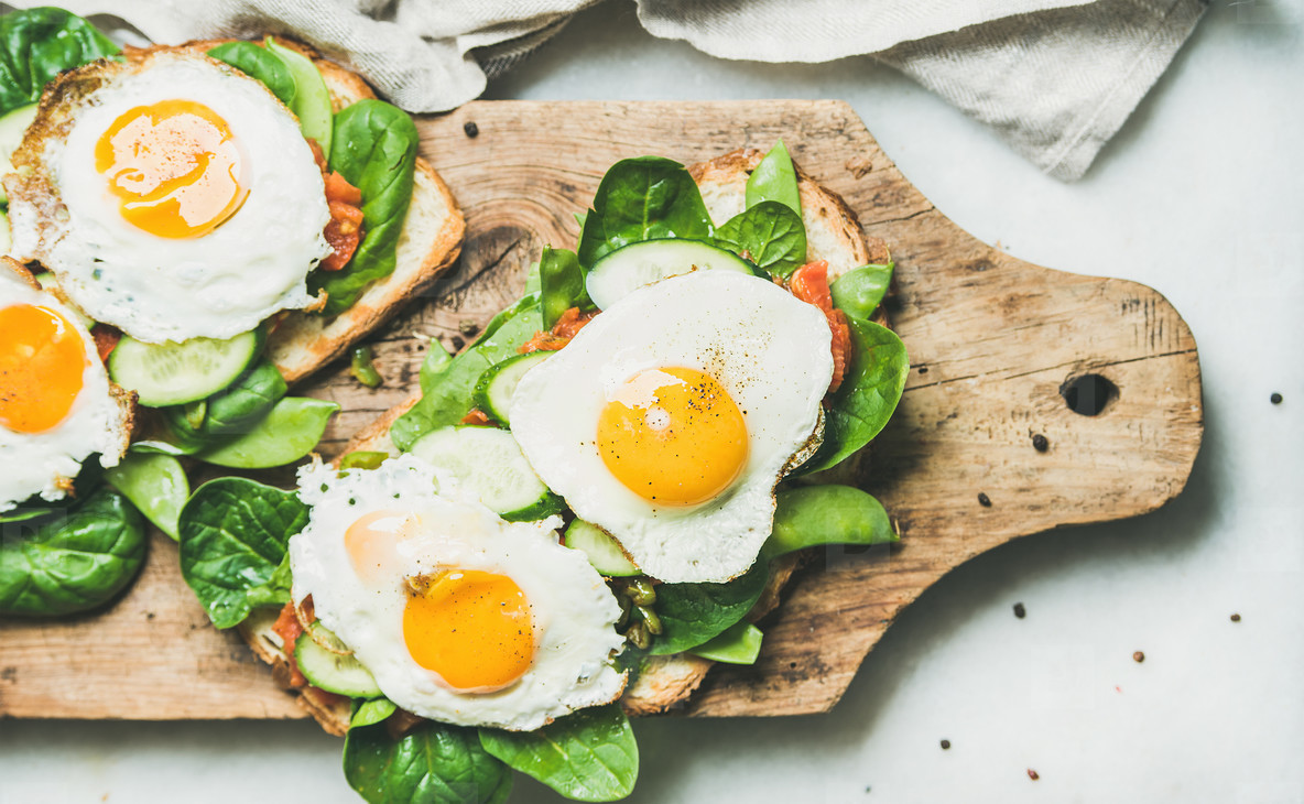Healthy breakfast sandwiches with fried eggs and fresh vegetables