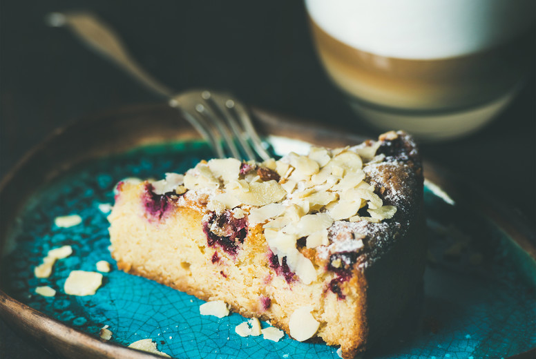 Piece of cake and glass of latte over dark background