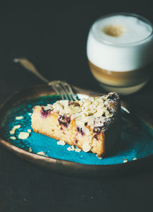 Piece of cake and glass of latte over dark background