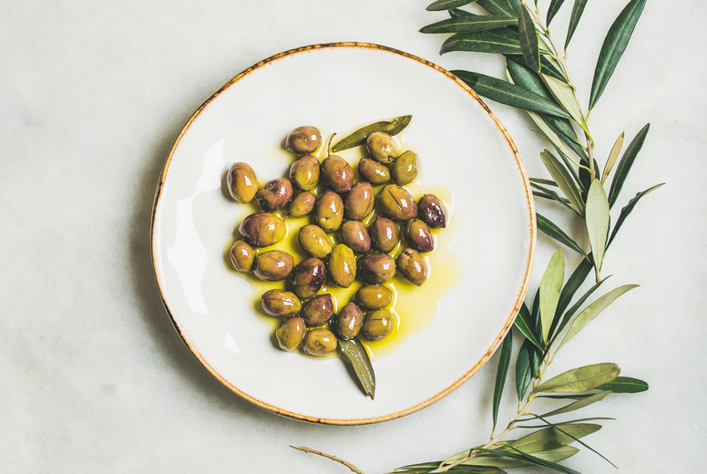 Pickled green Mediterranean olives in virgin olive oil on plate
