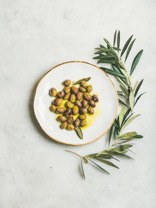 Pickled green Mediterranean olives in virgin olive oil on plate