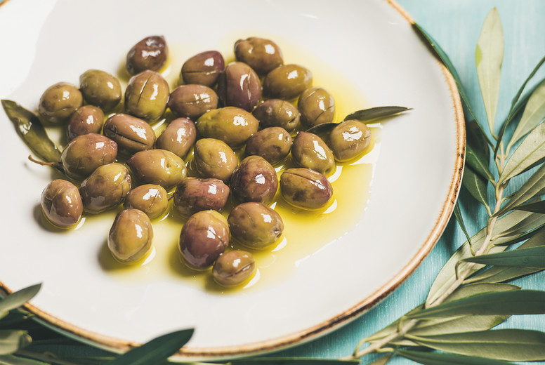 Pickled green olives, olive tree branch, virgin oil, selective focus