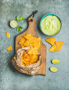 Mexican corn chips and fresh guacamole sauce on wooden board