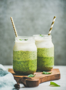 Ombre layered green smoothies with straws in glass jars