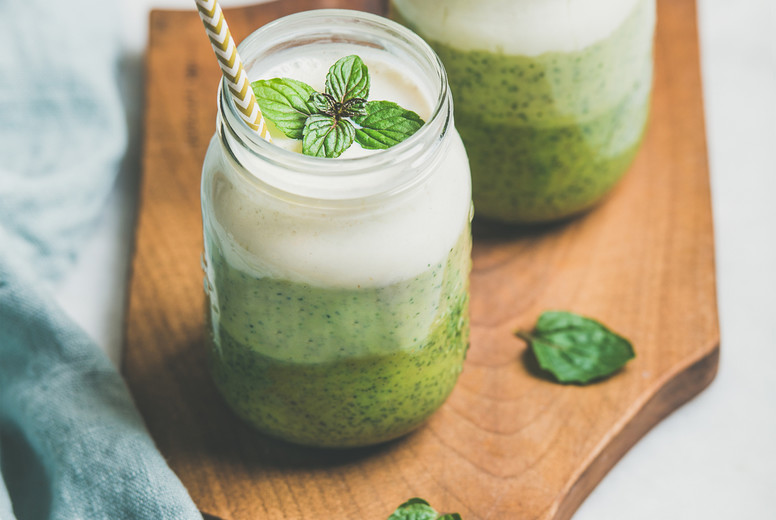 Ombre layered green smoothies in glass jars with straws