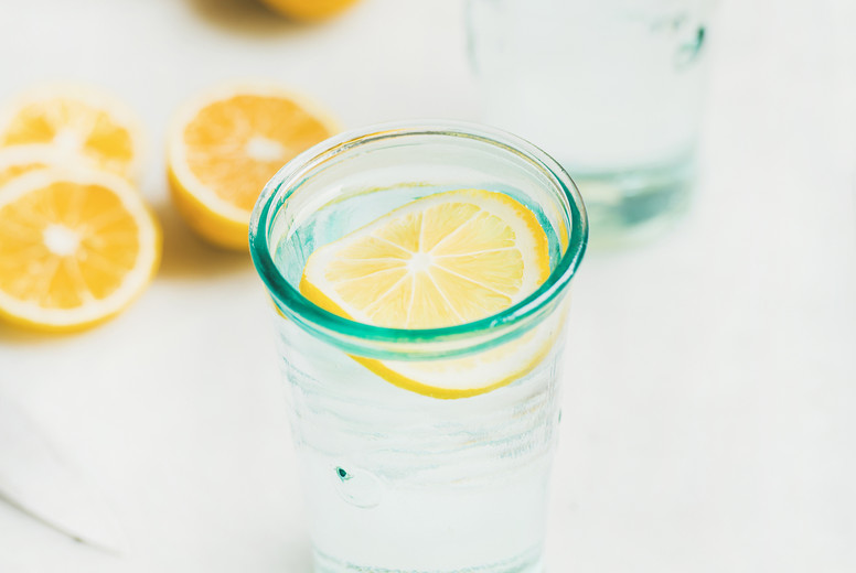Morning detox lemon water in glasses served with fresh lemons