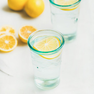 Morning detox lemon water in glasses served with fresh lemons