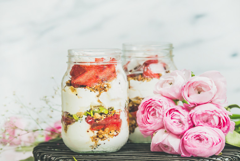 Healthy spring breakfast jars with pink raninkulus flowers, square crop
