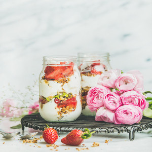 Healthy spring breakfast jars with pink raninkulus flowers square crop