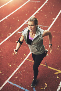 Athletic young woman running on track field