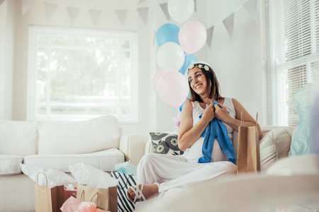 Smiling woman with new gifts at baby shower party