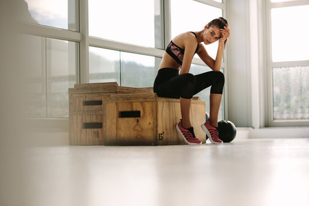 Exhausted fitness woman resting at gym