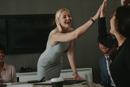 Businesswomen high five in a board room meeting