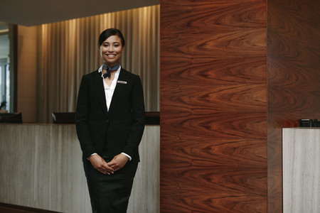 Female receptionist standing at hotel front desk