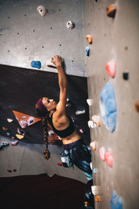Woman climbing indoor boulder wall