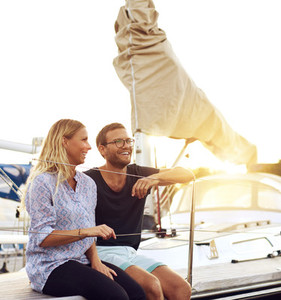 Happy Couple Sitting In front of a Sail Boat