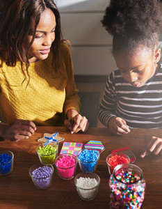 Black parent and child making beaded objects