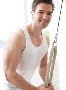 Smiling Muscular Young Guy Pulling Down Pulley