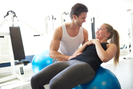 Fitness Trainer Assisting a Woman on Exercise Ball