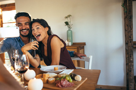 Couple taking selfie at dinner party indoors