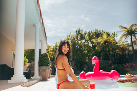 Attractive girl in bikini relaxing at poolside