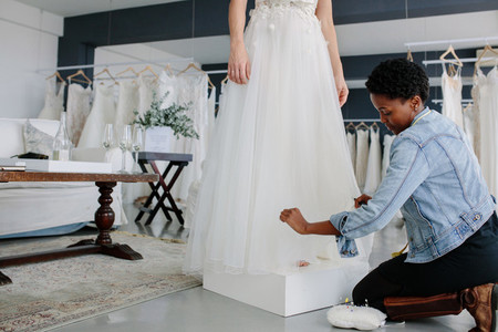 Female designer making adjustment to bridal gown