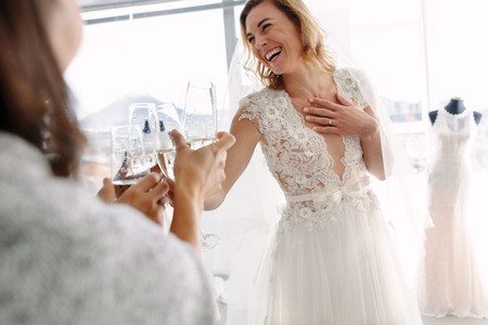 Bride toasting champagne with friends in bridal boutique