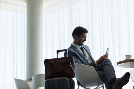 Businessman sitting at airport lounge with mobile phone