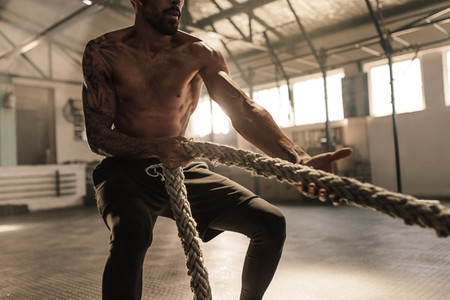 Athlete doing exercises with rope at gym