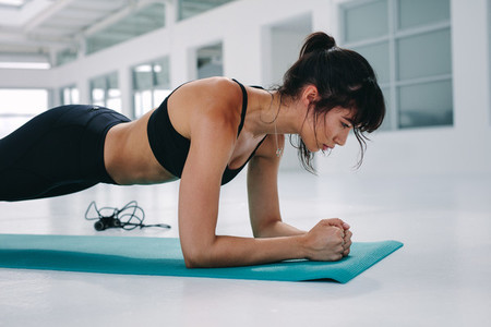 Muscular young woman doing planks exercise