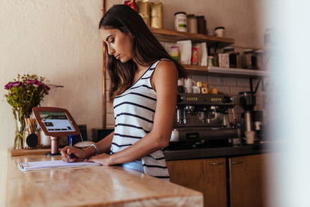 Woman entrepreneur standing at the billing counter of her cafe