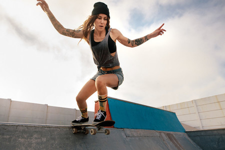 Cool young woman skateboarding at skate park