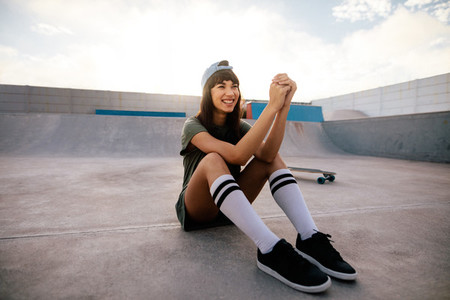 Cool female skateboarder relaxing outdoors at skate park