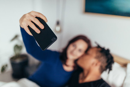 Couple on bed taking selfie