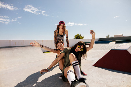 Female friends having fun with skateboard in the skate park