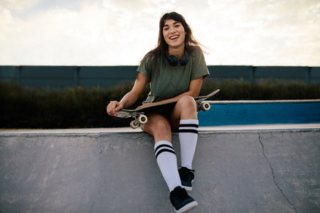 Attractive woman sitting on ramp at skate park
