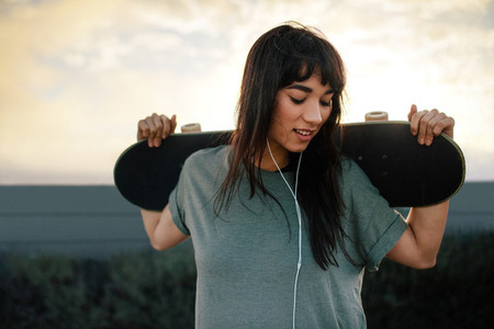 Female skateboarder standing outdoors with her skateboard