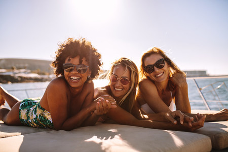 Cheerful women sunbathing on private yacht