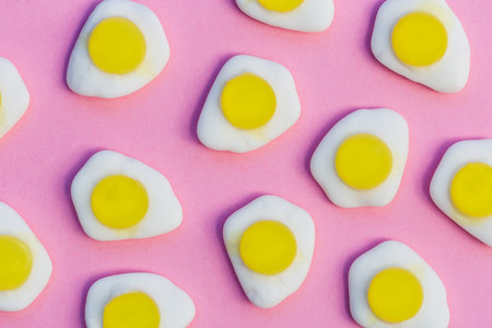 Fried eggs candy sweets on pink background